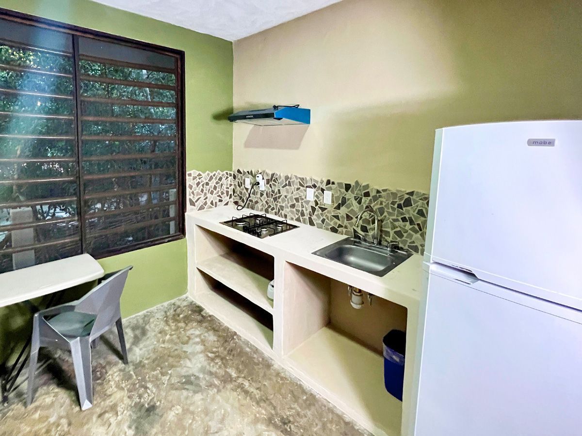A kitchen with a refrigerator , stove , sink , table and chairs.