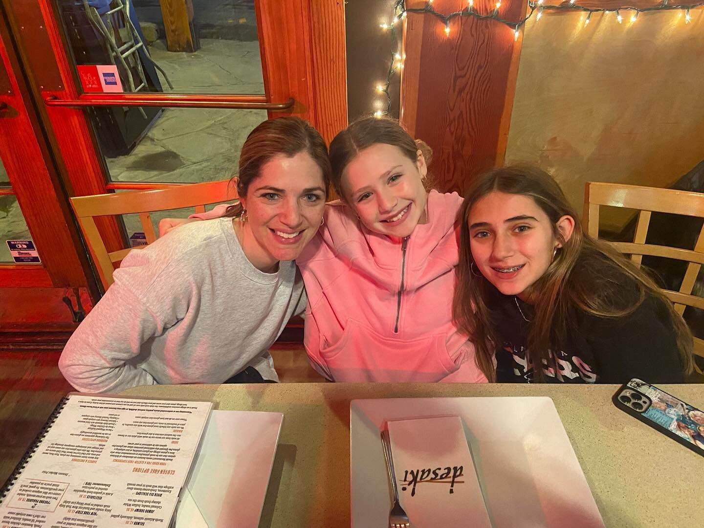 A woman and two girls are sitting at a table in desaki