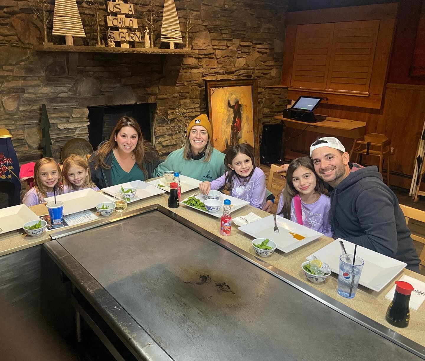 A family is sitting at a table in a restaurant eating food at desaki