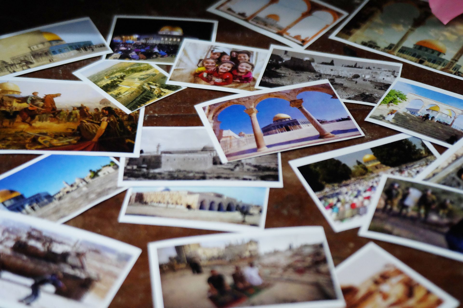 Dispersas fotografías impresas que muestran escenas de viajes y lugares emblemáticos sobre una mesa.