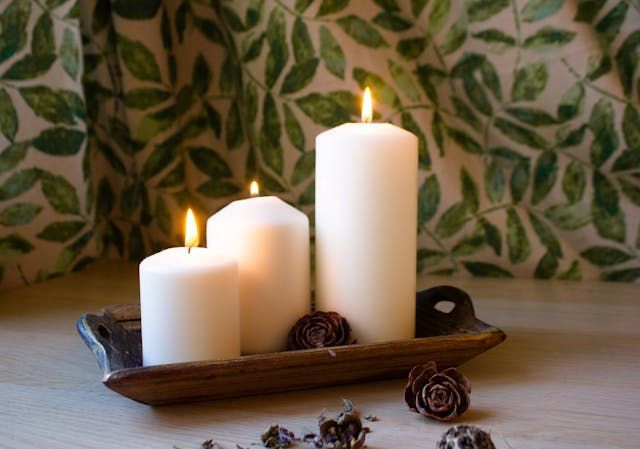 Three white candles glowing on a wooden tray create a calm feel for direct cremation Albuquerque, NM