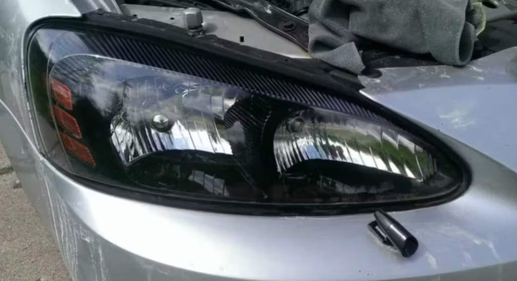 A close-up of a silver car with a dark-tinted, modified headlight assembly.