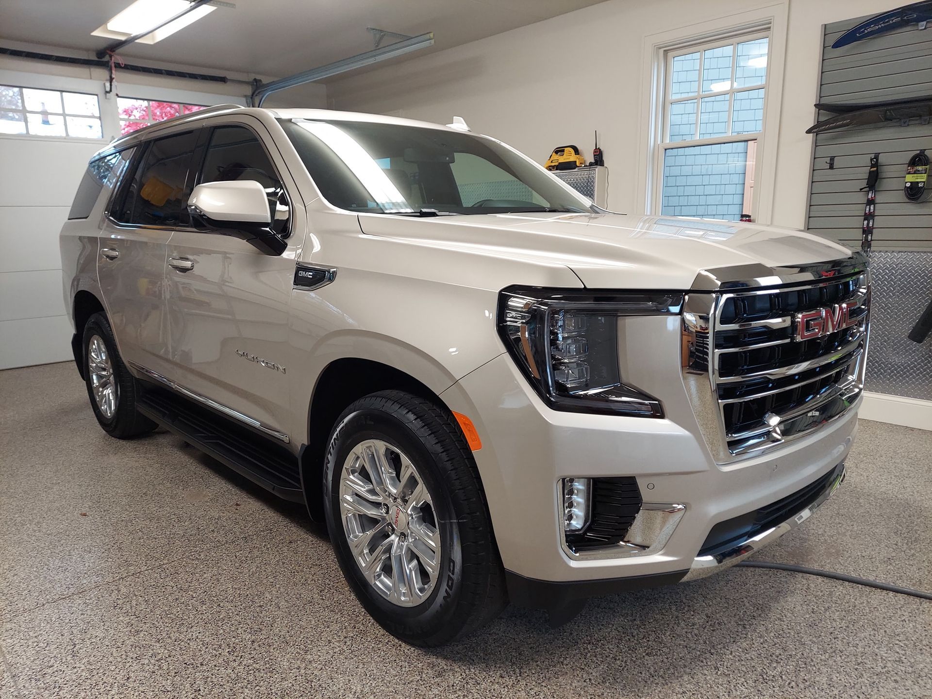 A silver gmc yukon is parked in a garage.