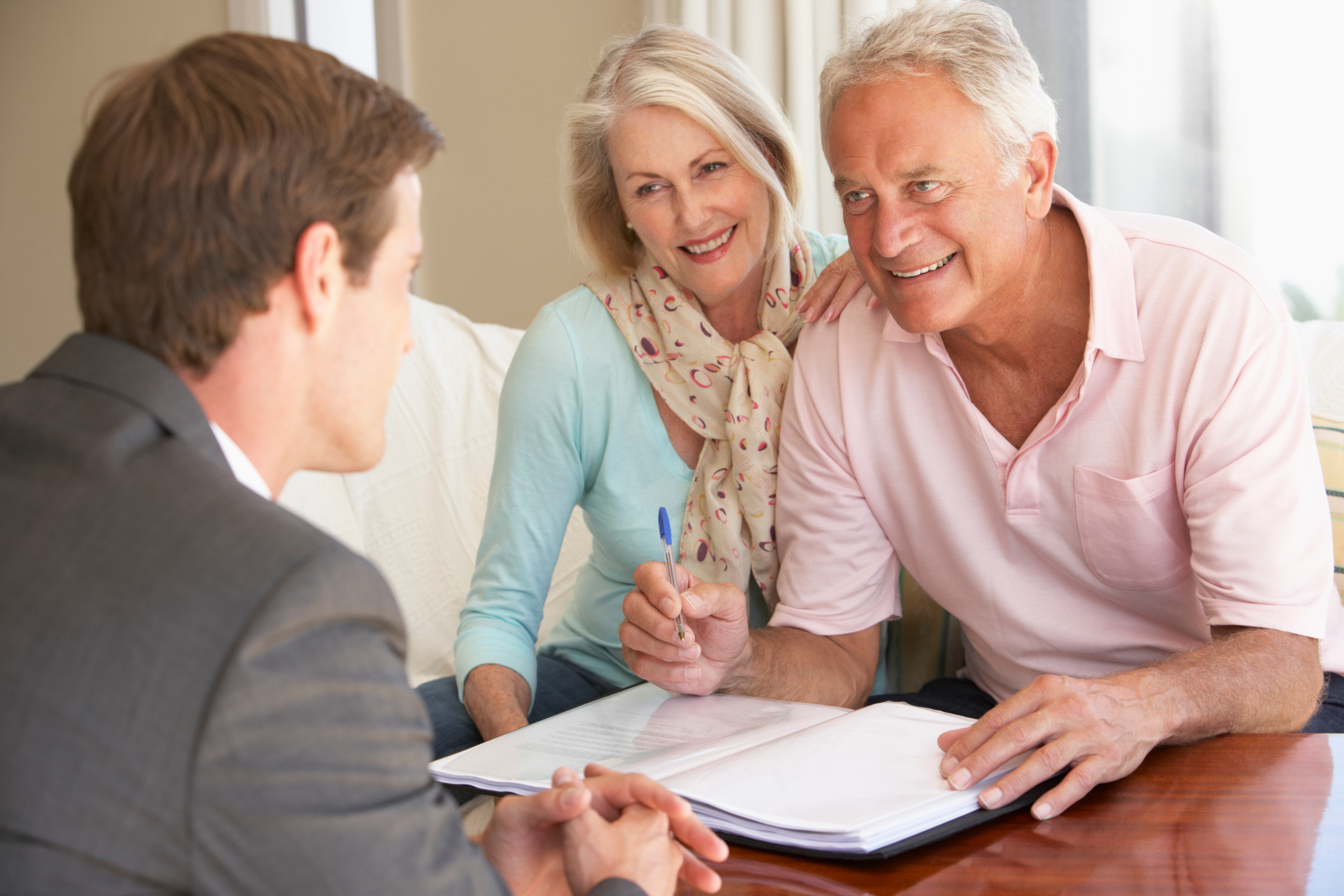 Two clients reviewing papers with a financial advisor at a desk
