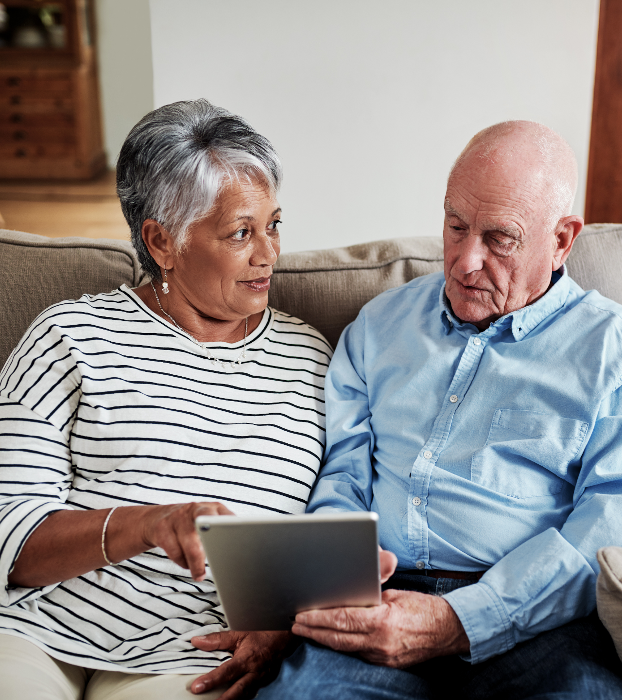 Two people on a couch looking at a tablet together