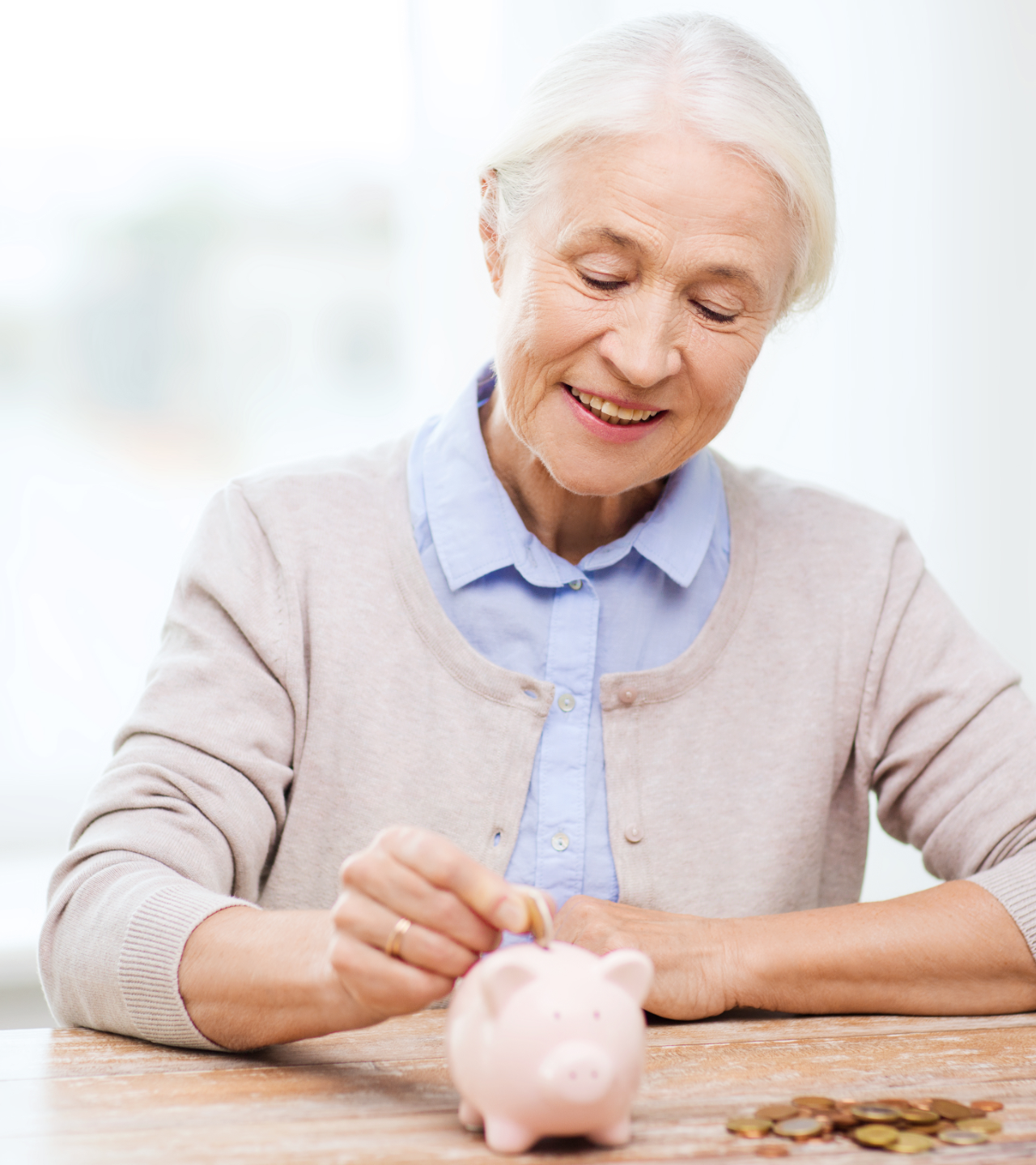 Woman placing coins into a pink piggy bank at a table