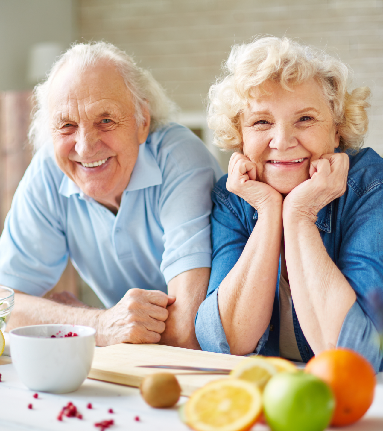 Smiling couple leaning on a table with fruit in a bright kitchen