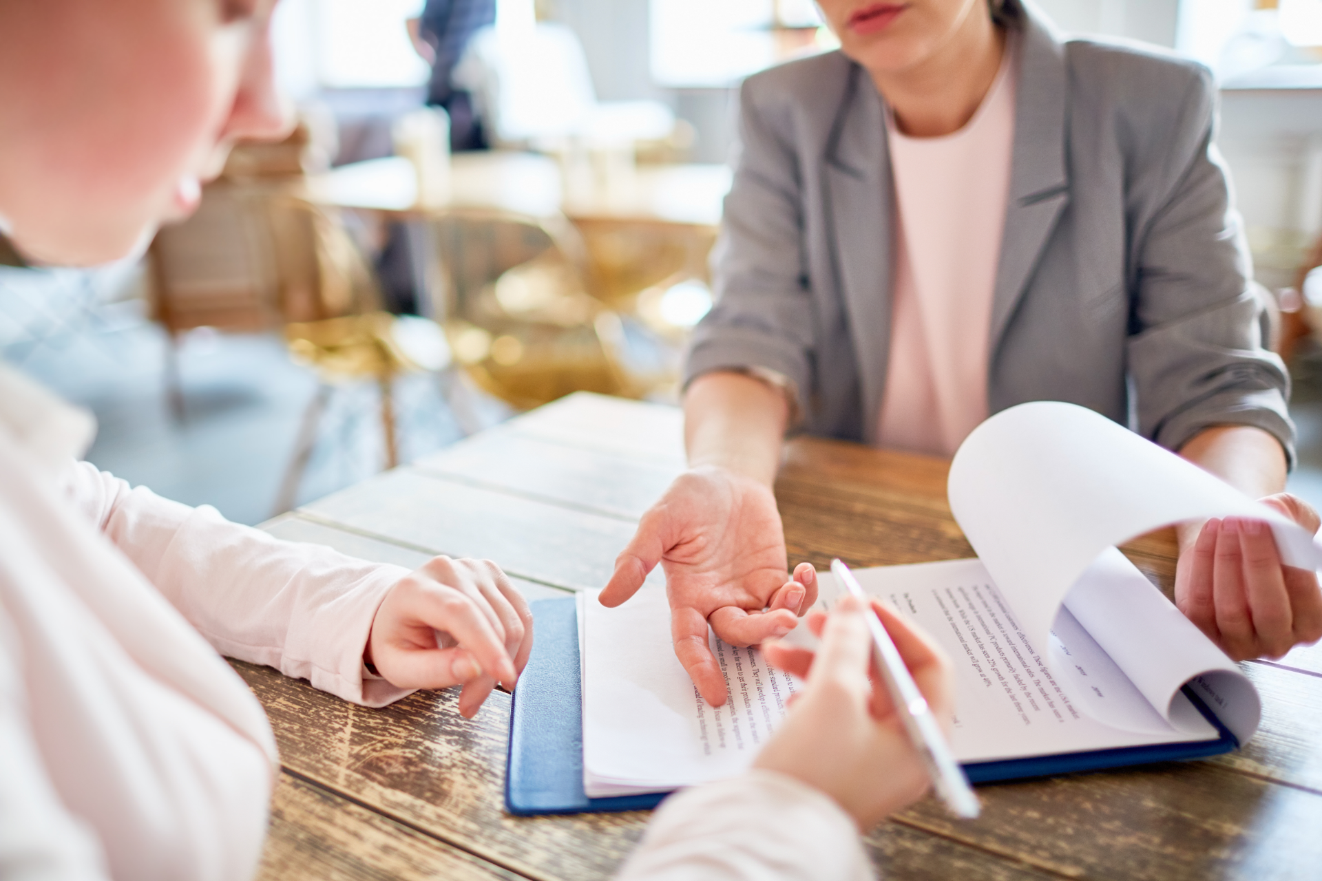 Two people discussing documents across a table in a bright office