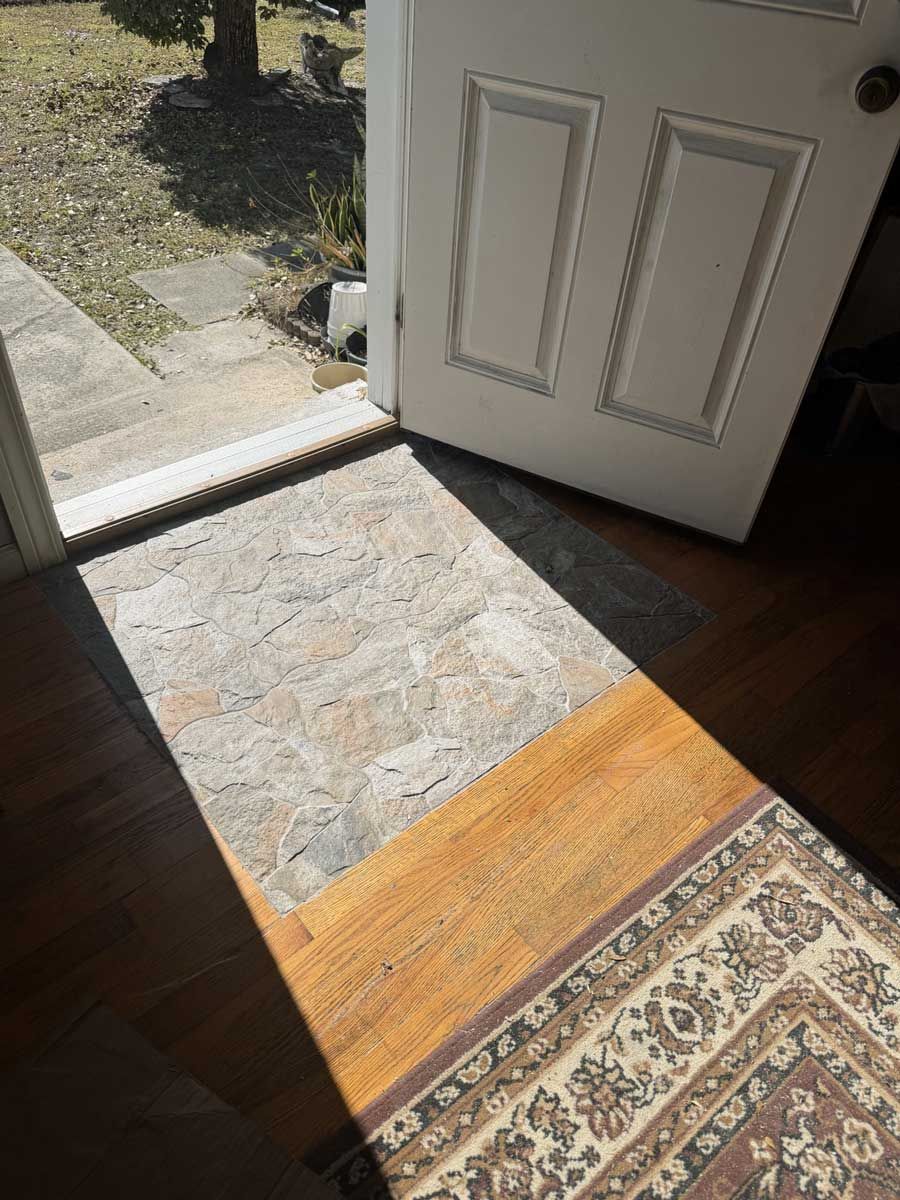 Open front door with sunlight on the threshold and a rug inside.