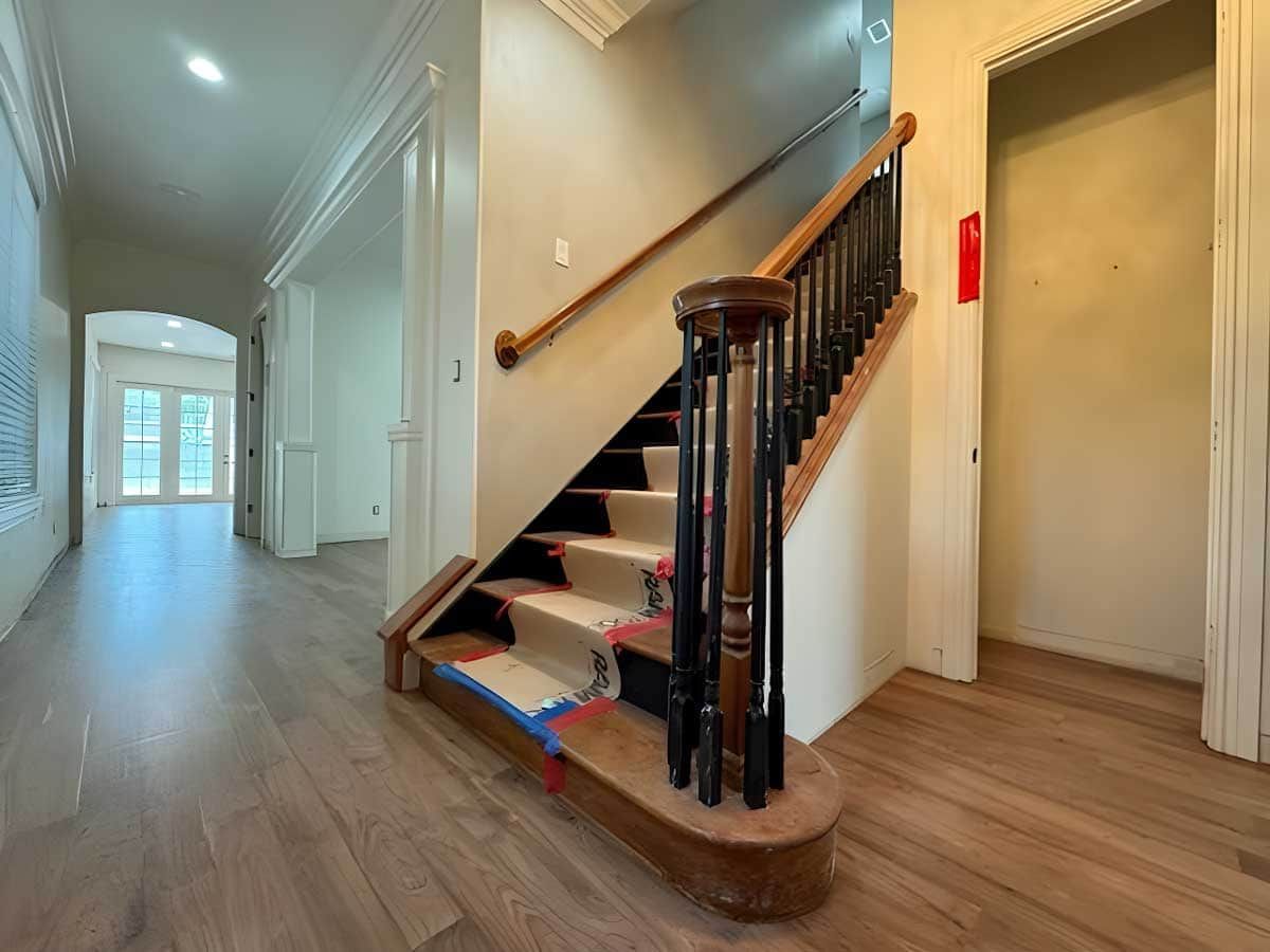 Hallway with stairs featuring a stairlift, wooden handrail, and elevator doorway on the right