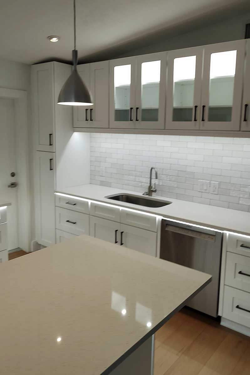 Bright modern kitchen with white cabinets, pendant light, and large island counter