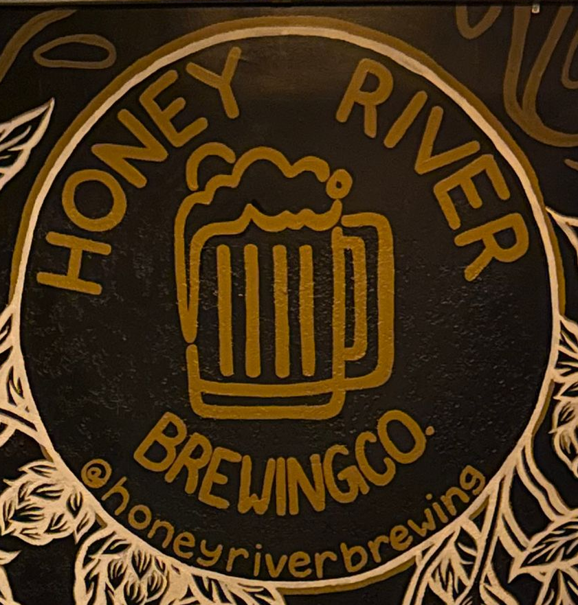 A Honey River Brewing Co. mural with a bench and pillows, in a dimly lit, cozy space.