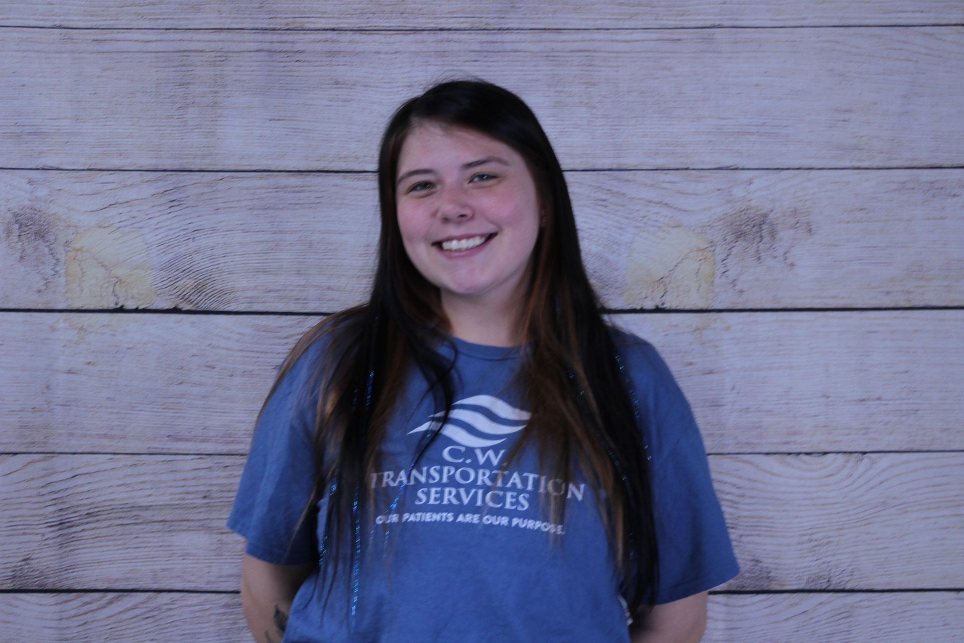 A person smiling while wearing a blue t-shirt with 