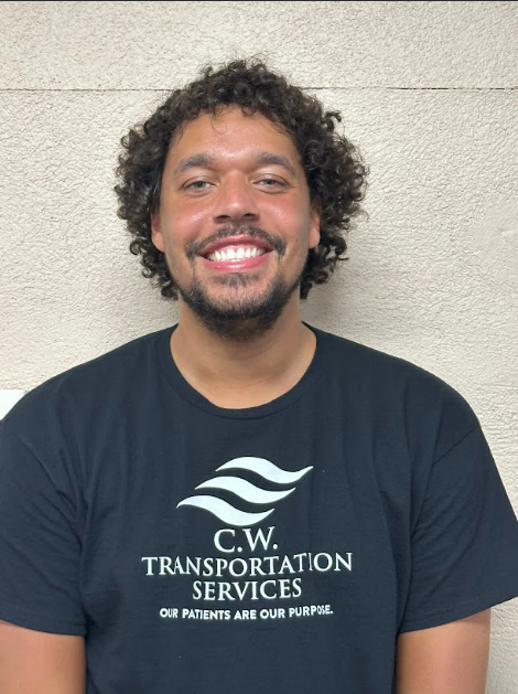 A person with curly hair smiles while wearing a dark T-shirt with the C.W. Transportation Services logo.
