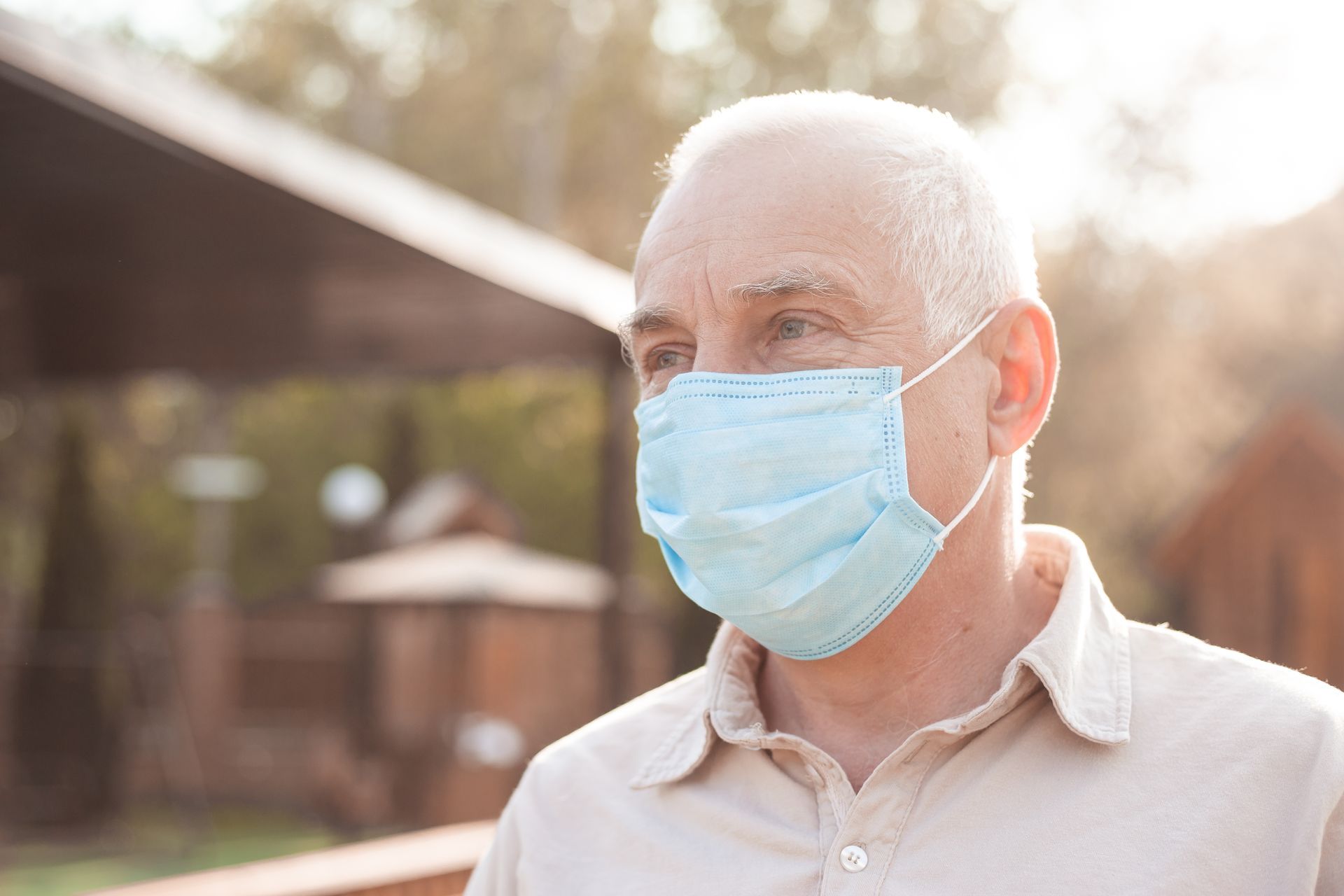 An elderly man wearing a medical mask outdoors.