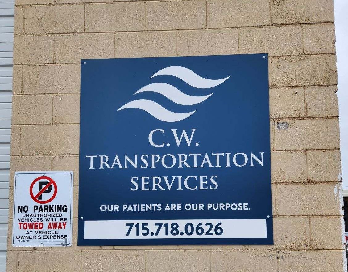 Sign for C.W. Transportation Services on a brick wall, featuring a white logo, company name, and the phone number 715.718.0626.