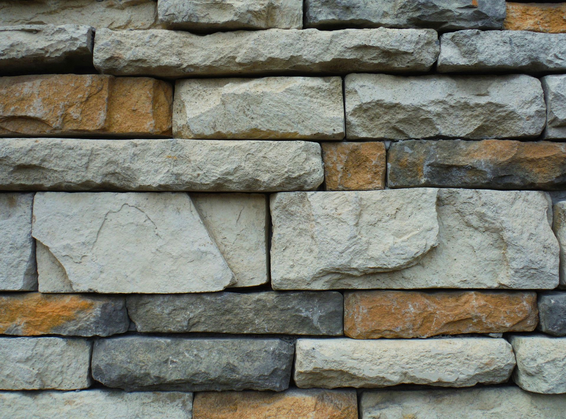 Close-up of a stone wall with rectangular blocks in shades of gray, tan, and brown.
