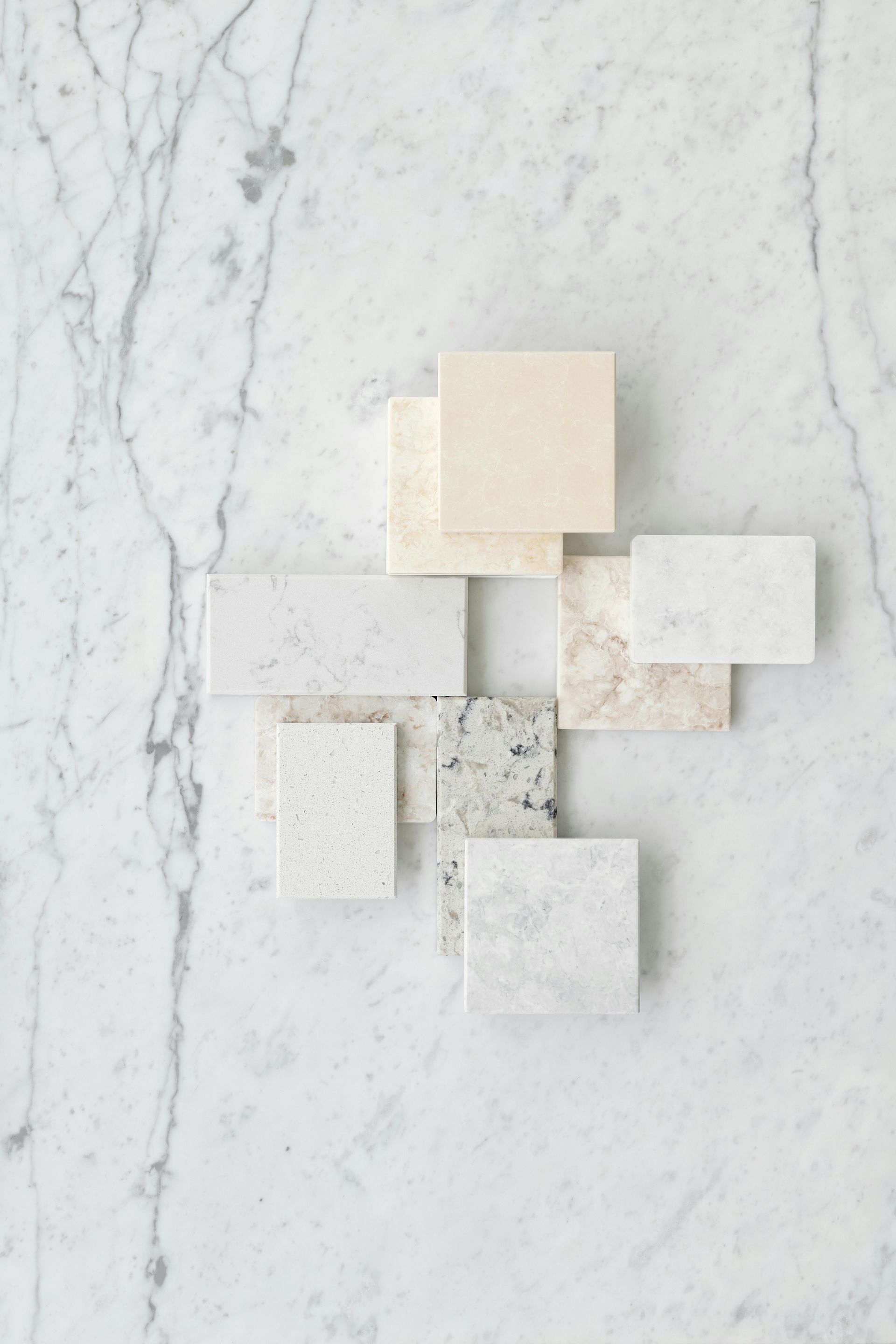 White marble background with several small, light-colored stone samples arranged on top.