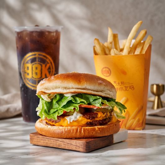Burger, fries, and iced soda on a table in a restaurant setting