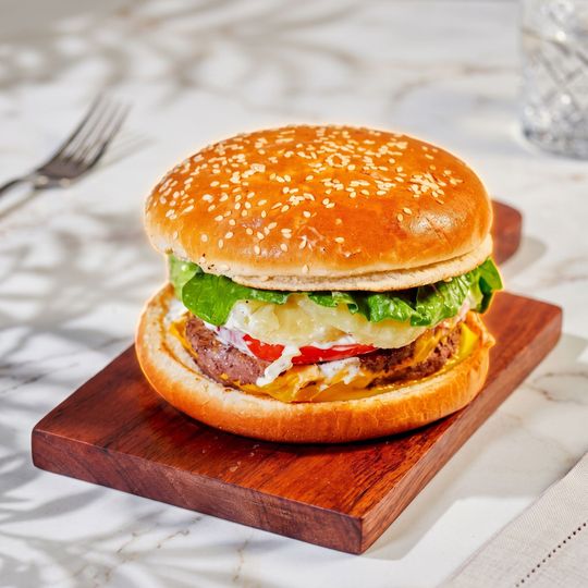 Sesame seed burger with lettuce and tomato on a wooden board