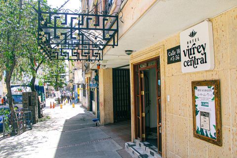 Entrada del Hotel Virrey Central, uno de los mejores hoteles de Bogotá, con fachada clara y acceso desde una calle arbolada en el centro de la ciudad.