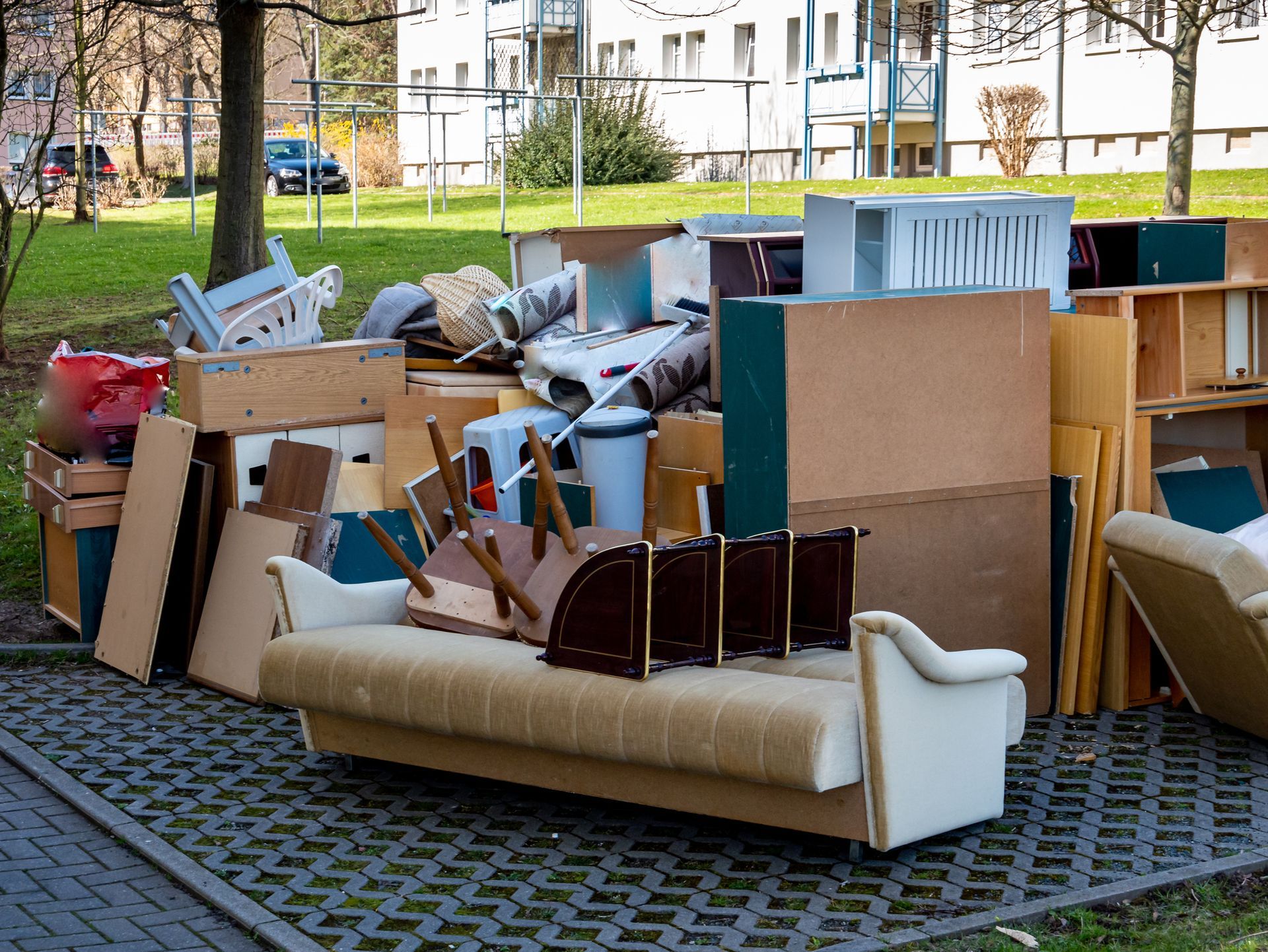 Pile of discarded furniture and debris on a paved area.