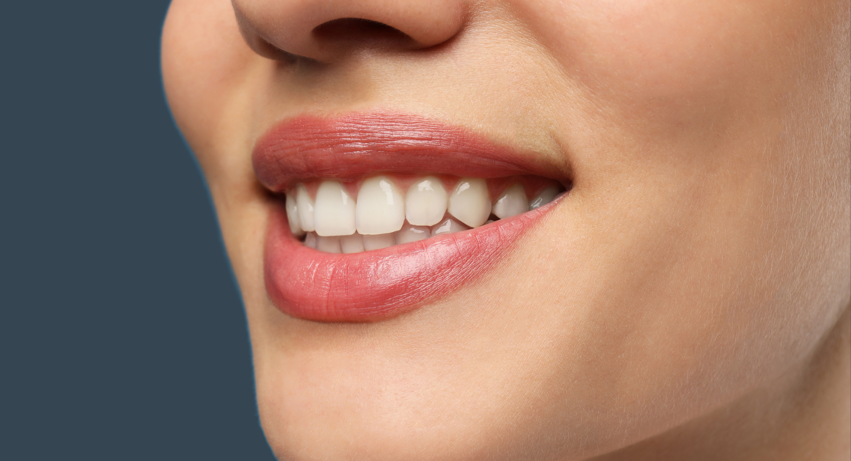 Close-up of a person's smiling mouth, showing white teeth and glossy, rose-colored lips.