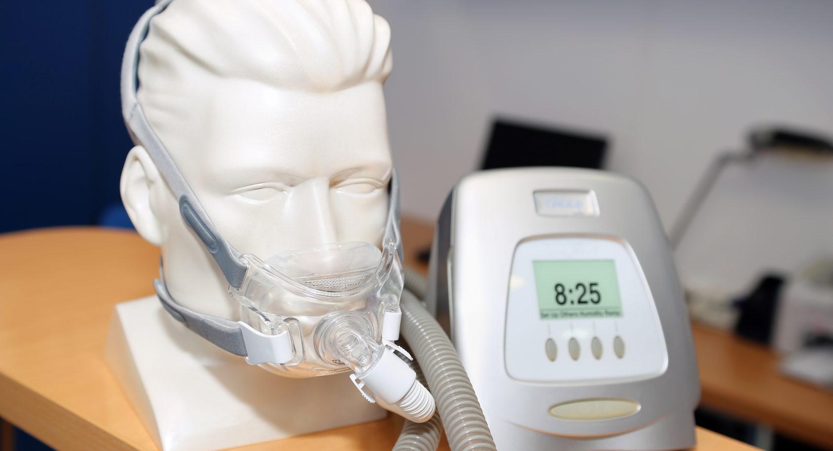Mannequin head wearing CPAP mask next to a CPAP machine with a digital display showing the time.