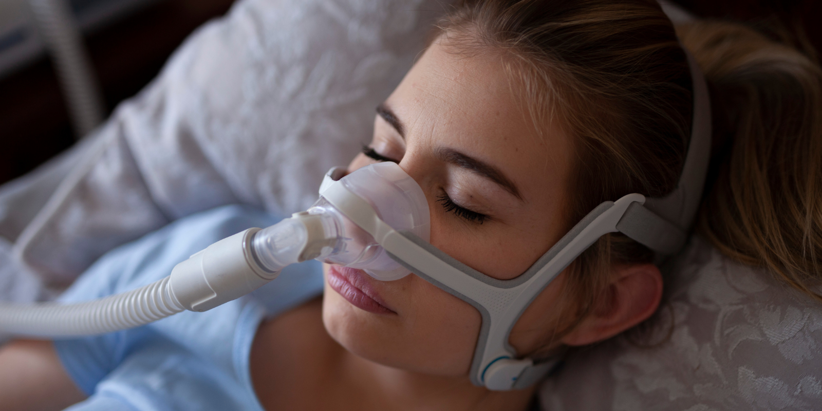 Woman sleeping with a CPAP mask on in bed