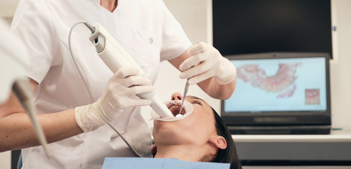 Dentist examining a patient’s open mouth with dental tools in a clinic