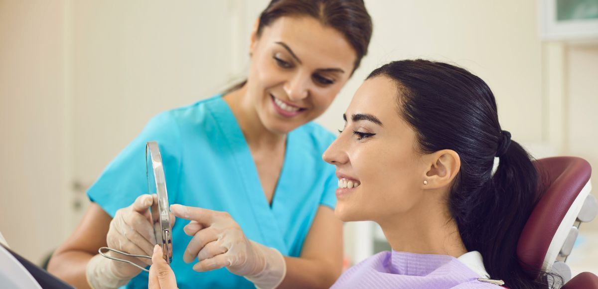 Dentist showing a patient a dental model while smiling in a clinic chair