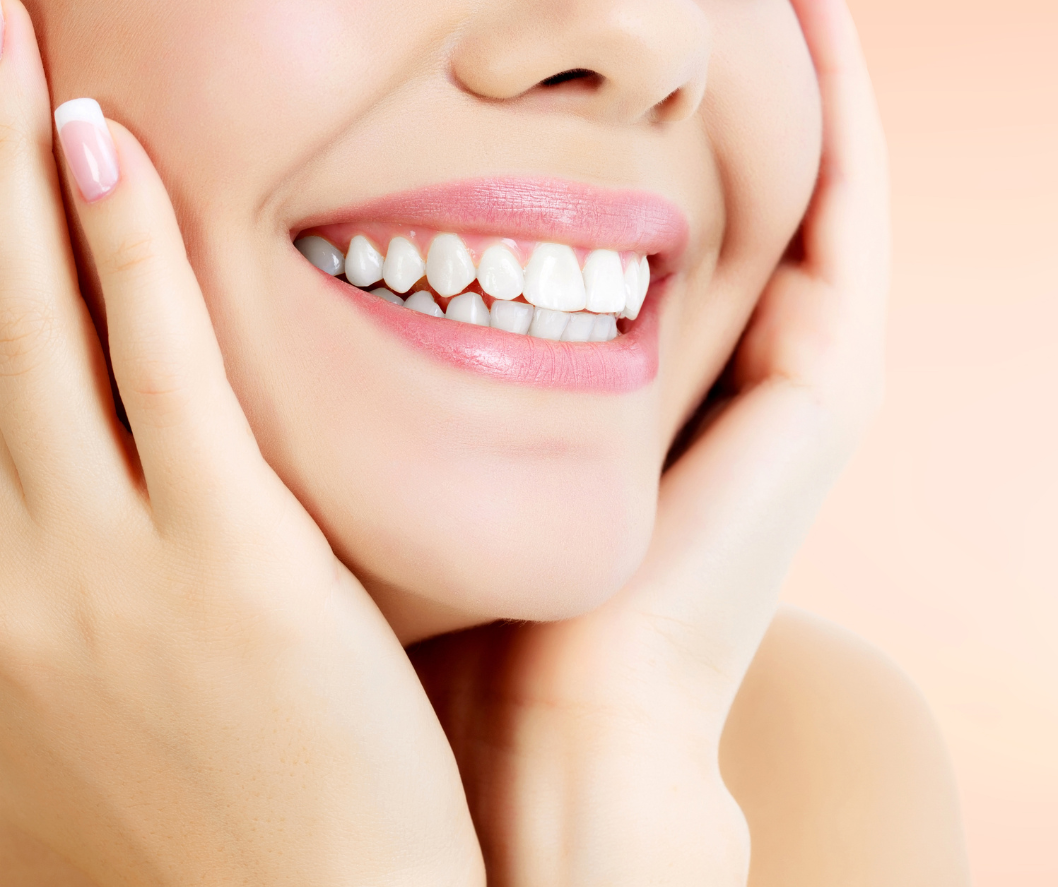Smiling mouth with hands framing face; showing white teeth and pink lips.