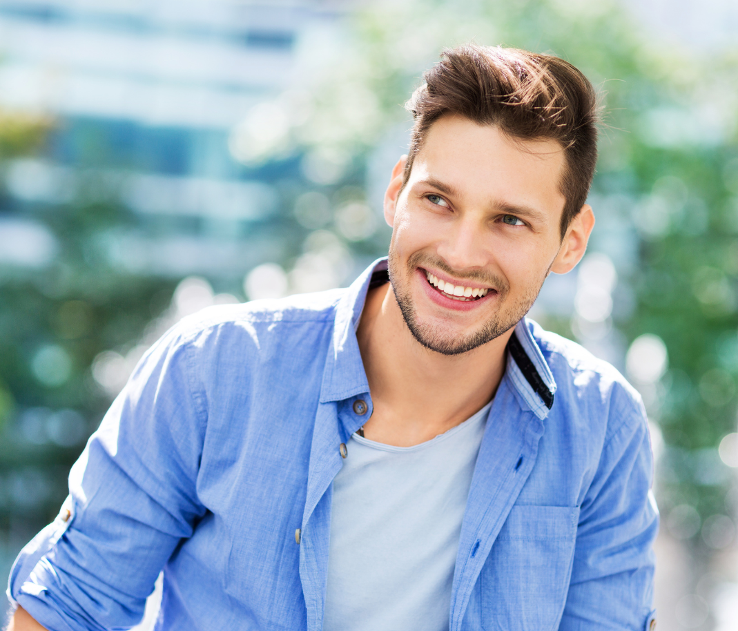 Man outdoors, smiling warmly in a blue shirt