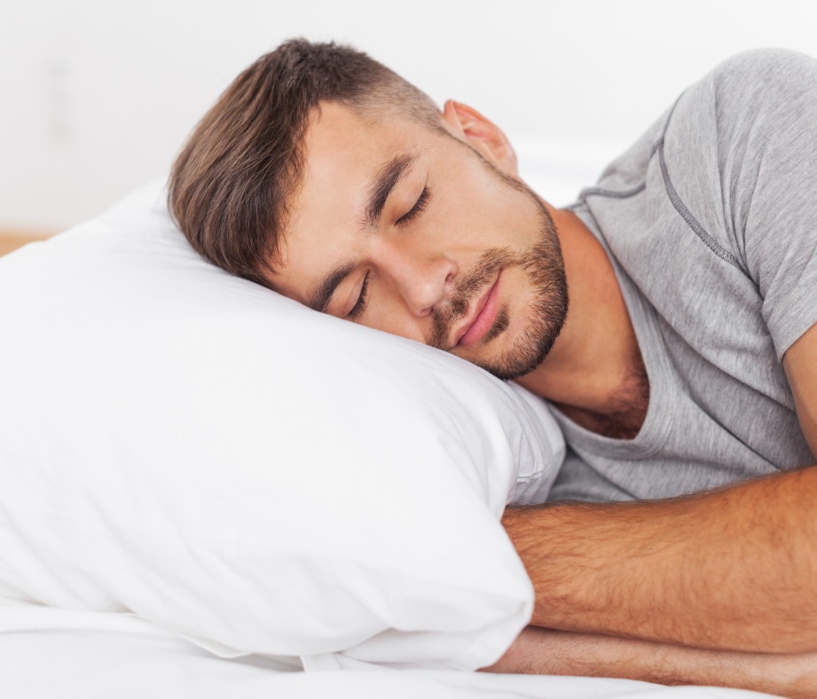 Man asleep on a white pillow, wearing a gray shirt.