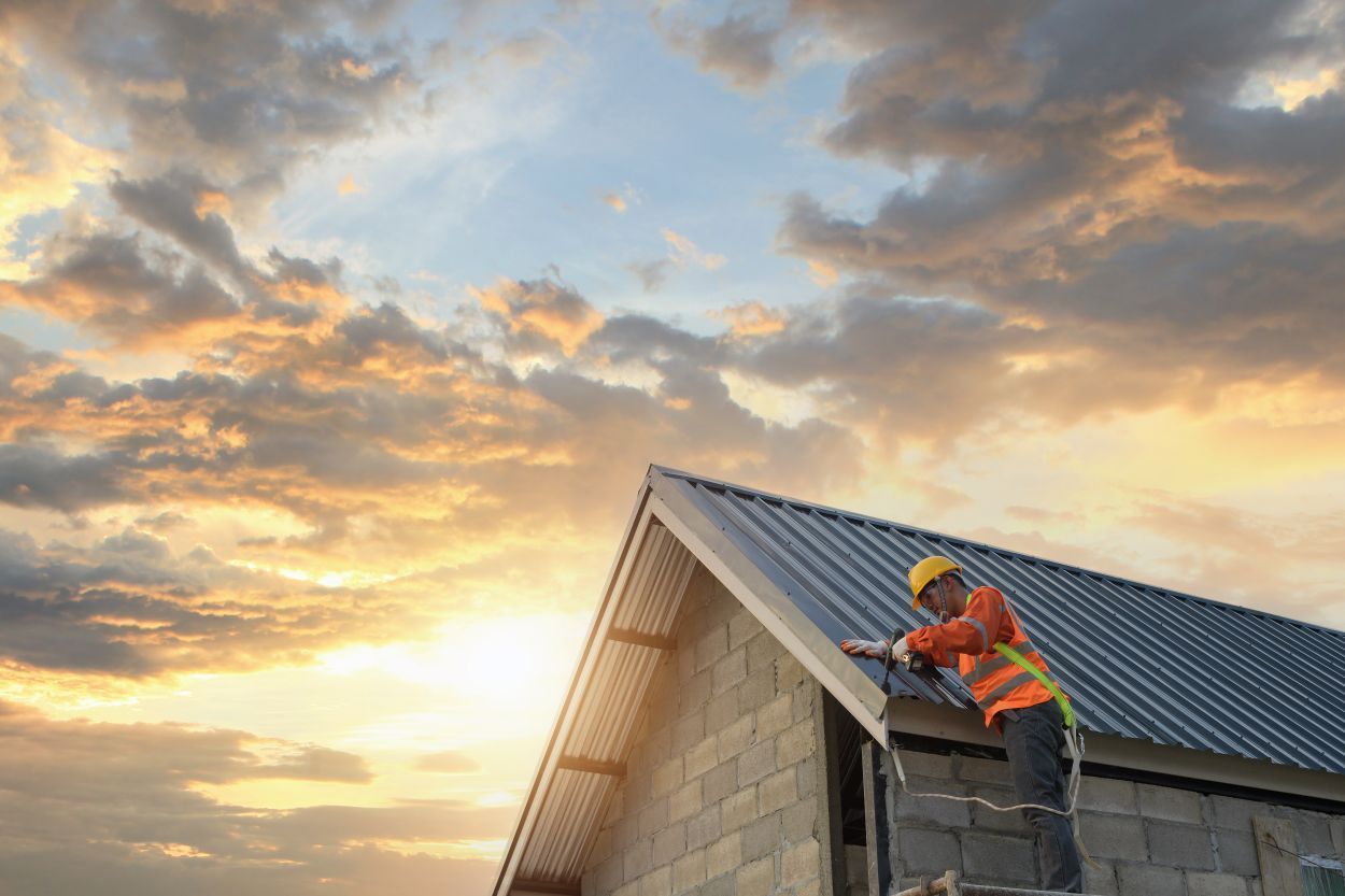 A construction worker is working on the roof of a house.