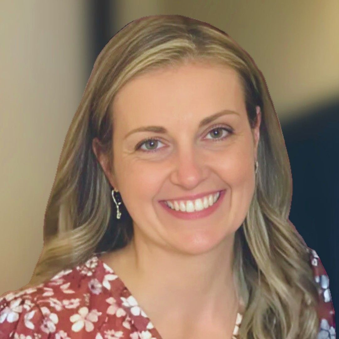 A smiling woman with long blonde hair, wearing a floral maroon top and delicate silver earrings.