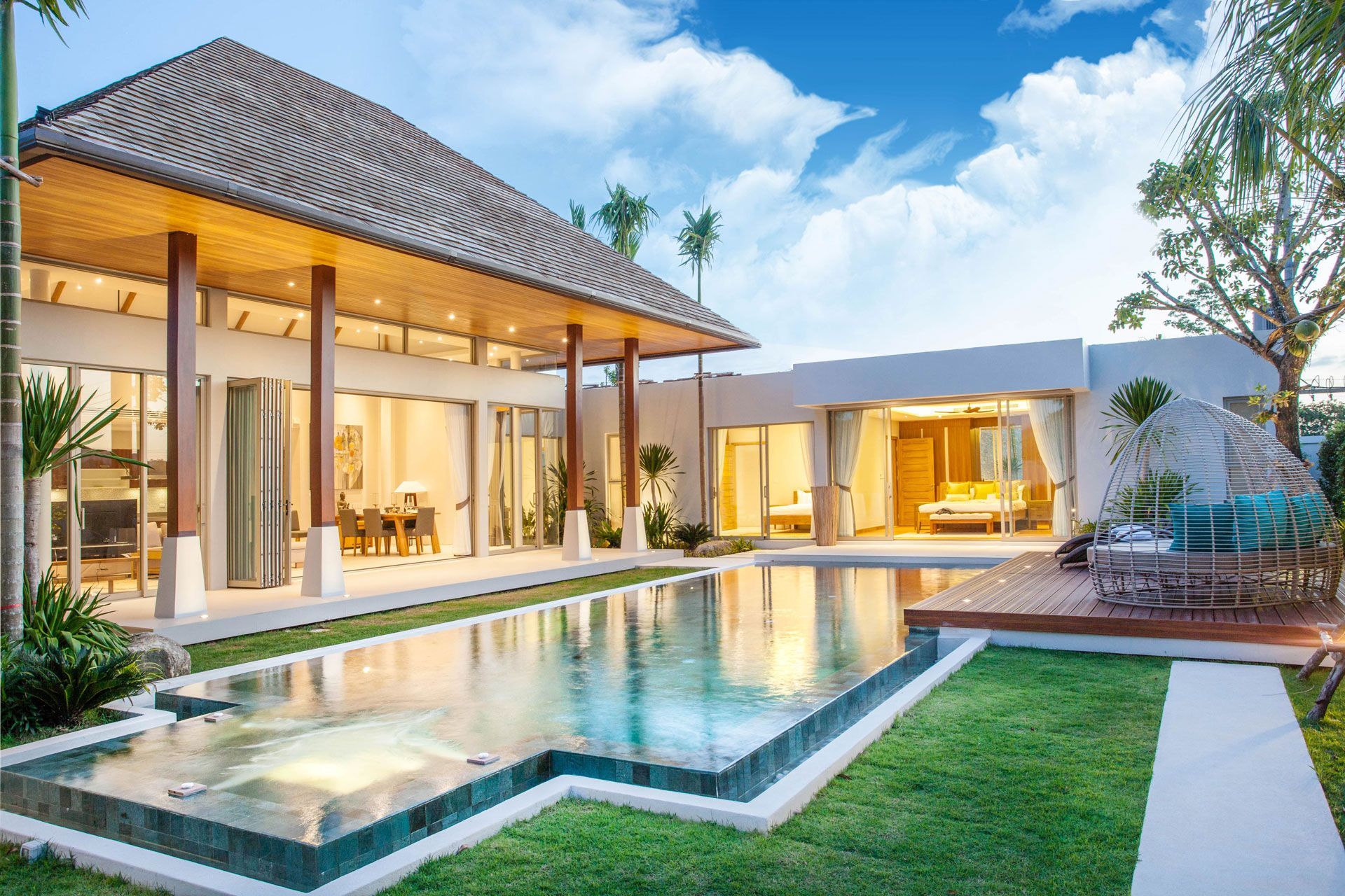 Luxury villa with swimming pool and lush green lawn under a bright blue sky.