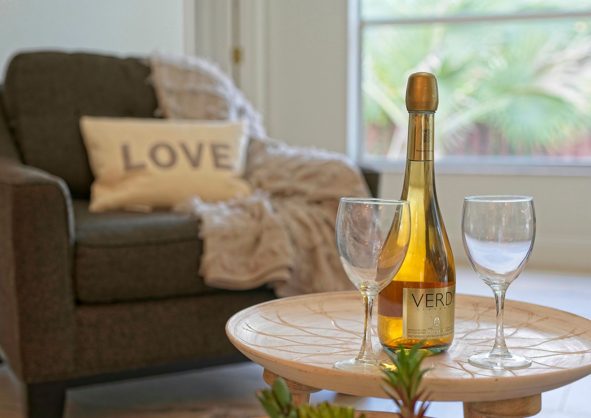 Champagne bottle and glasses on a wooden table, with an armchair and 