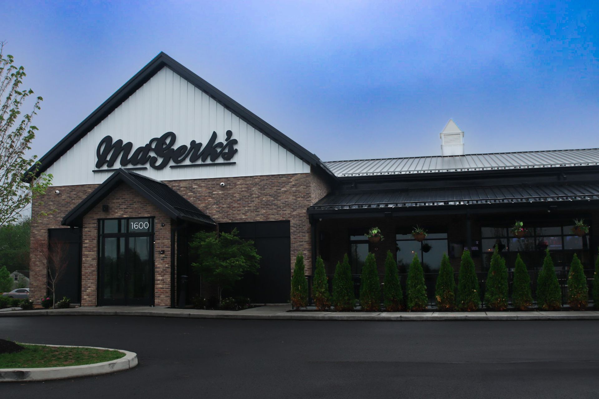 Exterior of MaGerks restaurant, tan brick and black trim building with sign, under a cloudy sky.