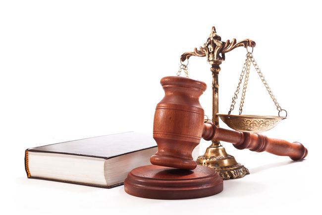 Wooden gavel, law book, and balance scale on a white background