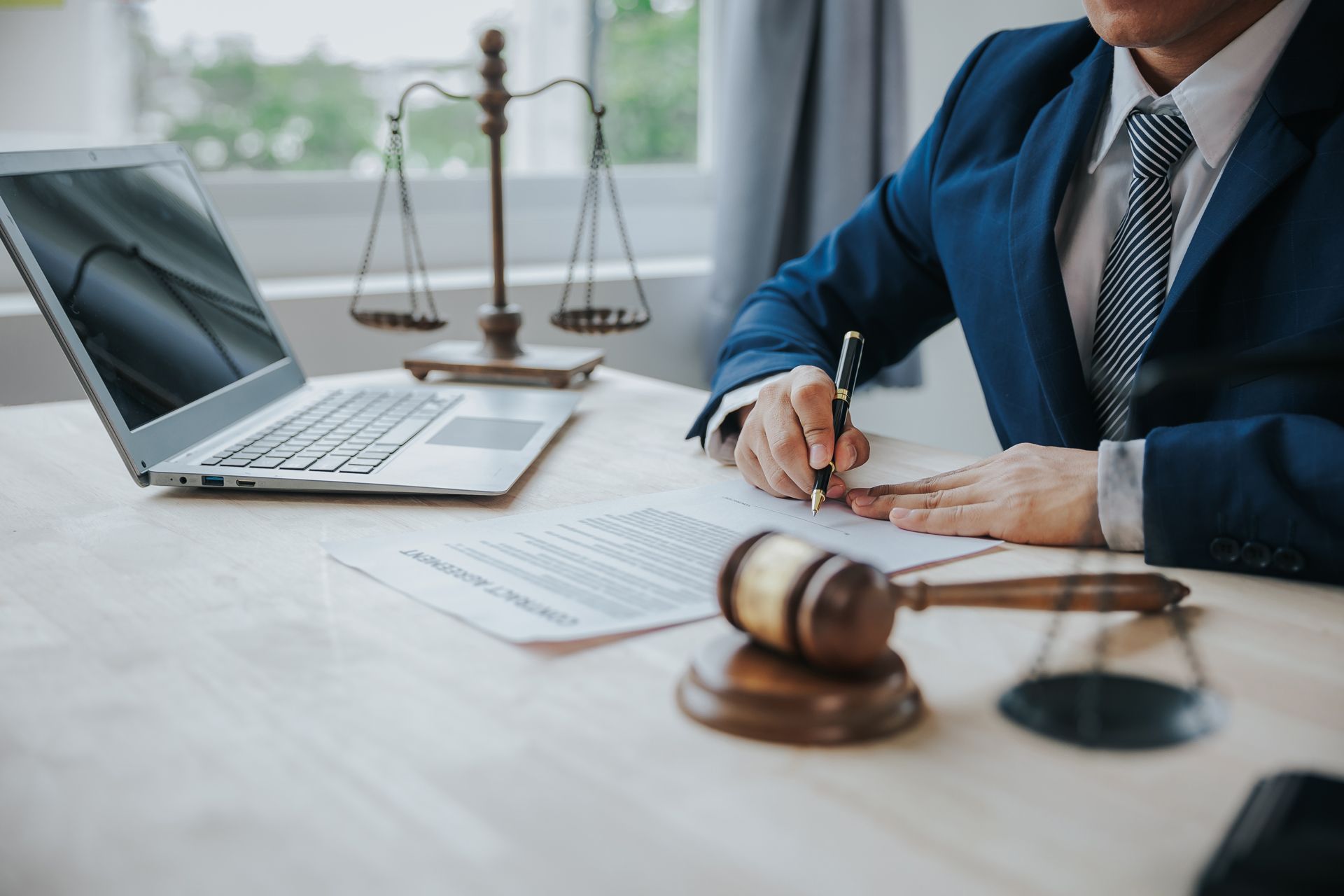 Lawyer at desk with laptop, gavel, and scales of justice in a bright office