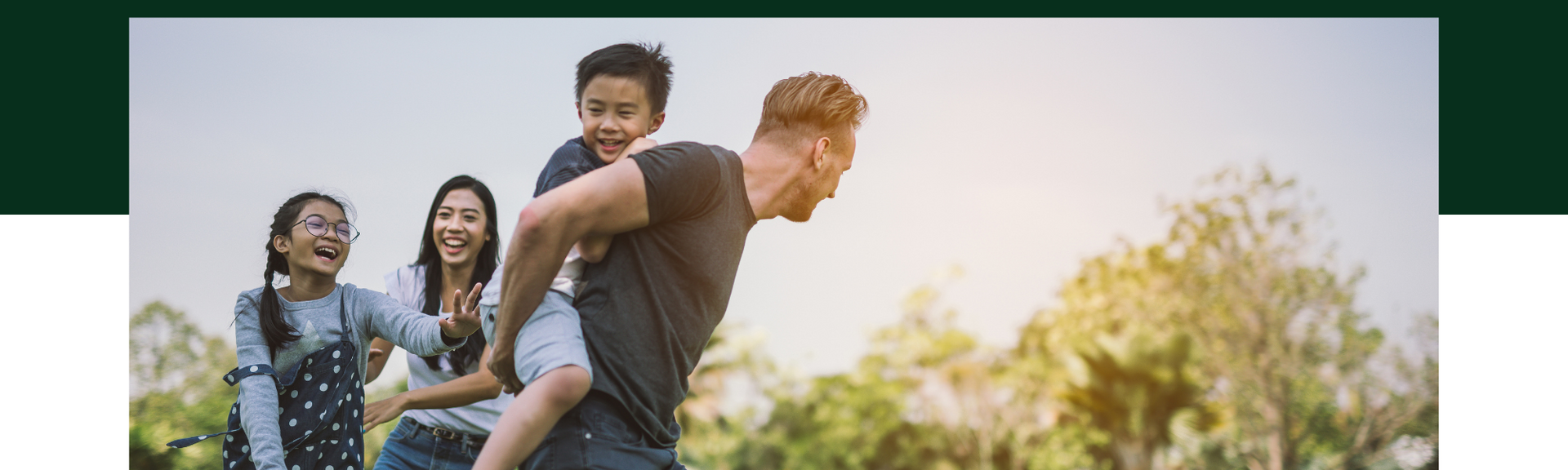 People hiking together outdoors, with one person giving another a piggyback ride in a sunny field.