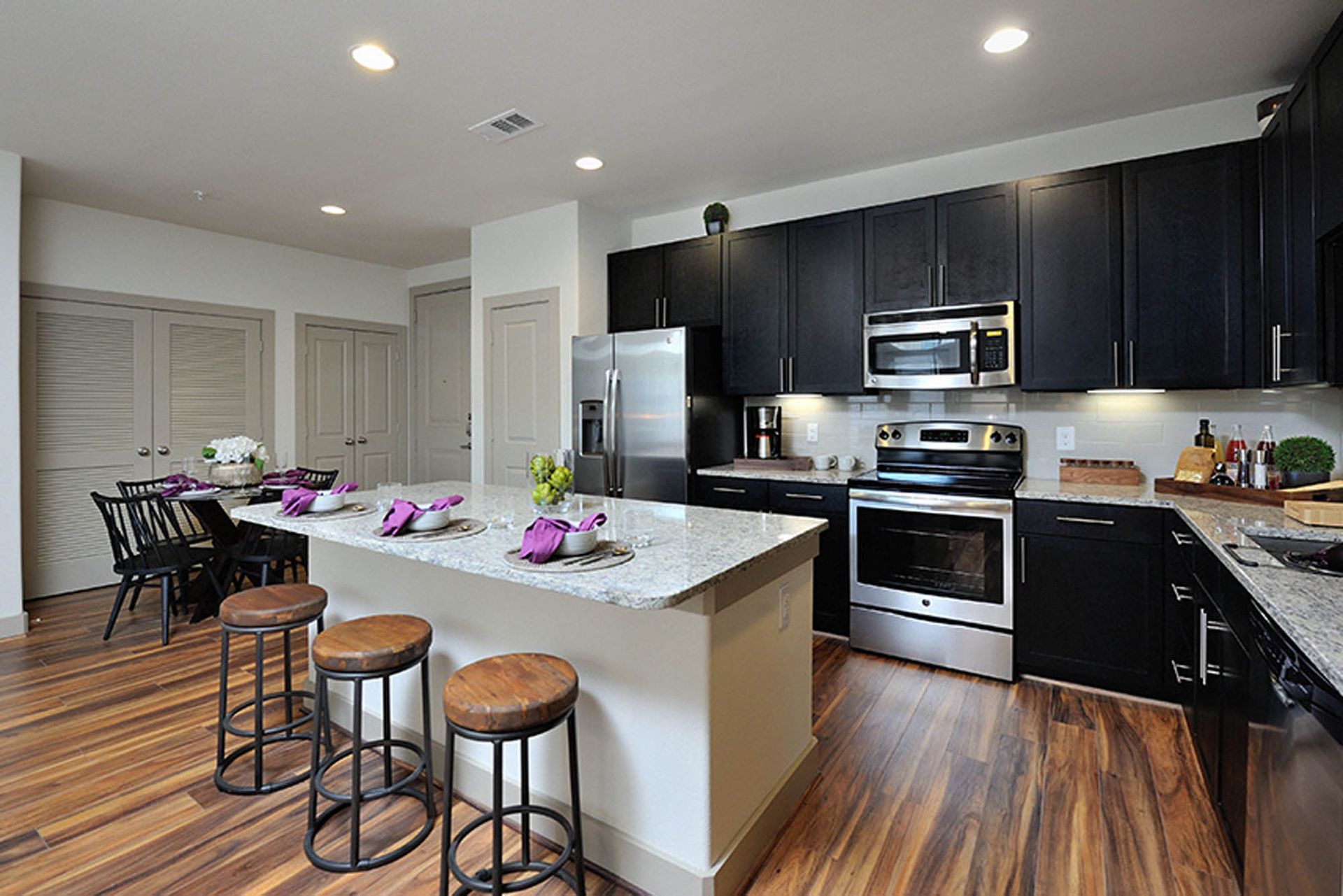 Modern kitchen with dark cabinets, stainless steel appliances, and a large island with seating.