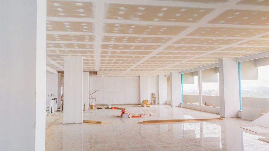 An unfinished interior space with a drywall ceiling featuring visible joints and screw holes, and white columns.
