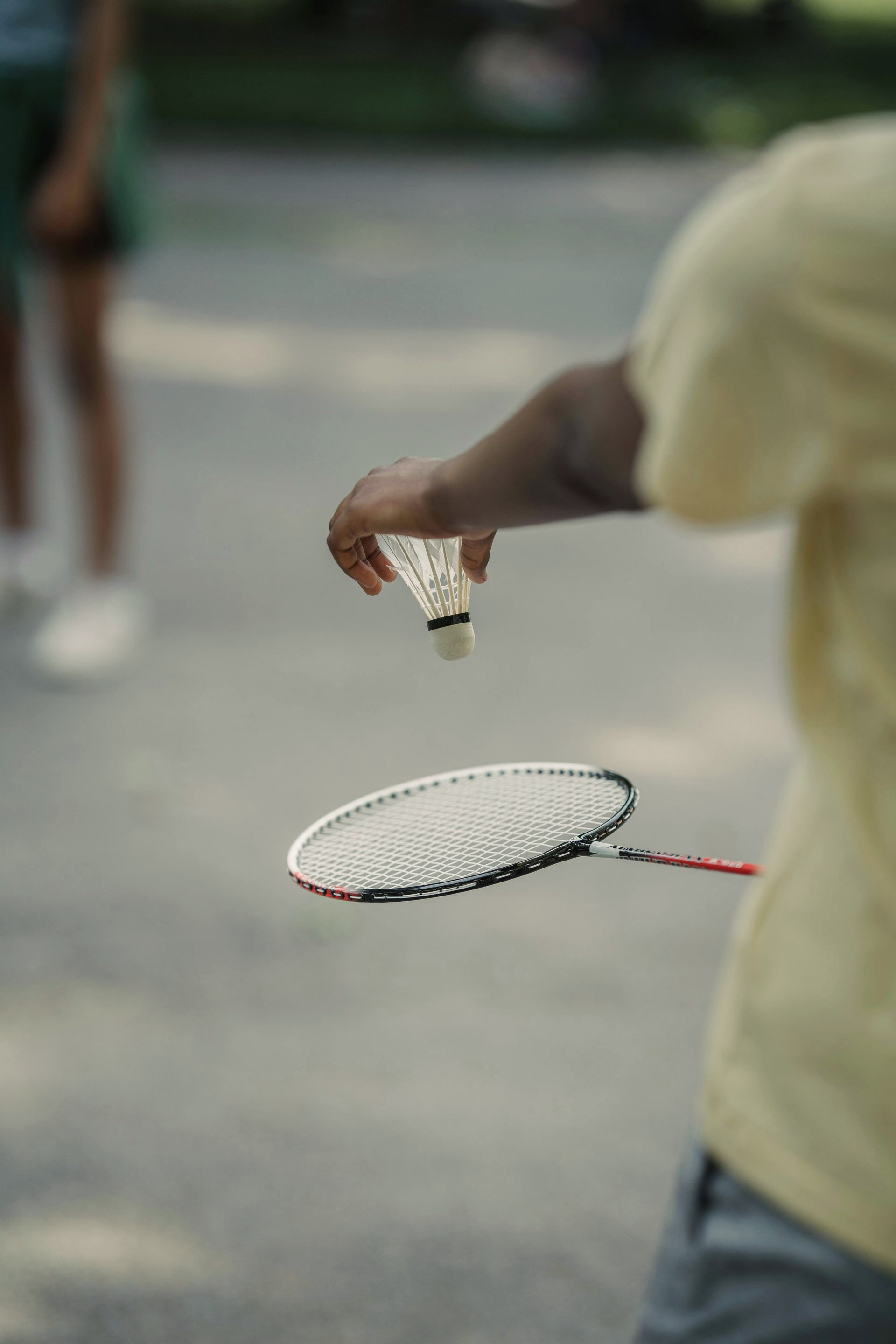 Een jongen in geel shirt die gaat serveren met een badminton shuttle