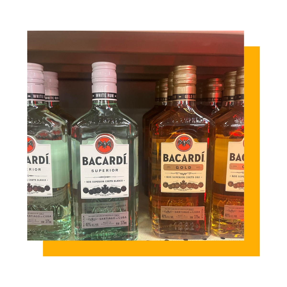 Bottles of Bacardi rum in various flavors on a store shelf, with an orange frame.