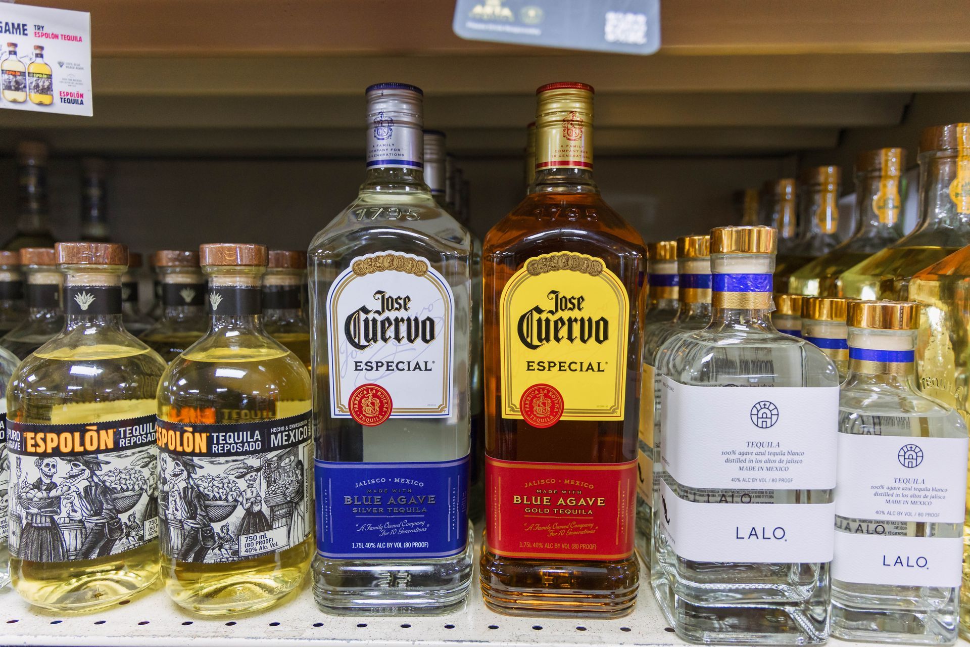Bottles of various tequilas on a store shelf.  Includes clear and amber tequila bottles.