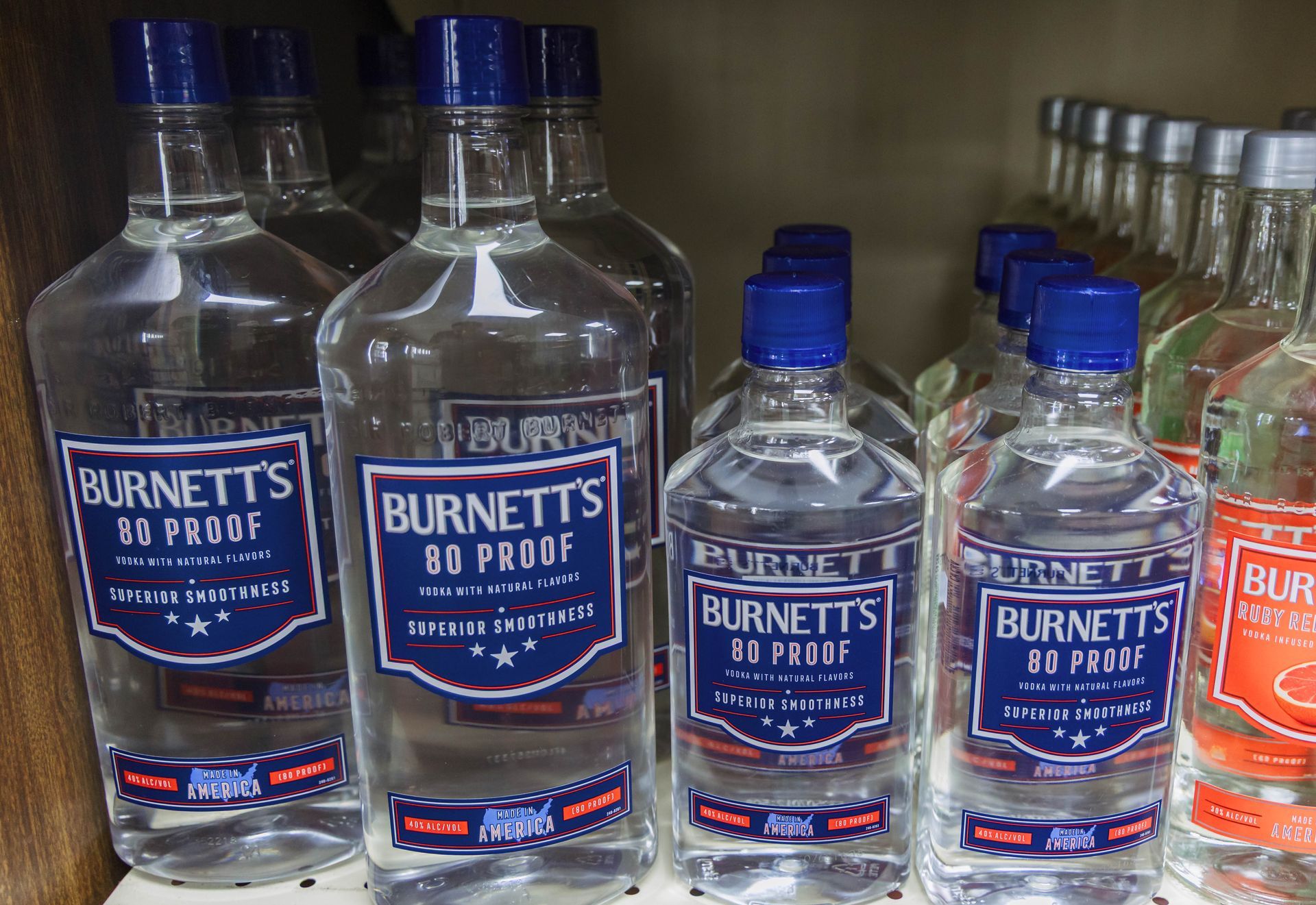 Bottles of Burnett's 80 proof vodka on a store shelf, with blue and red labels.