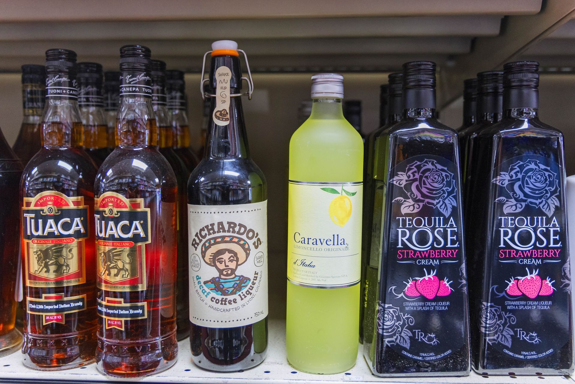 Liquor bottles on a shelf, including Tuaca, Richardson's, Caravella, and Tequila Rose.