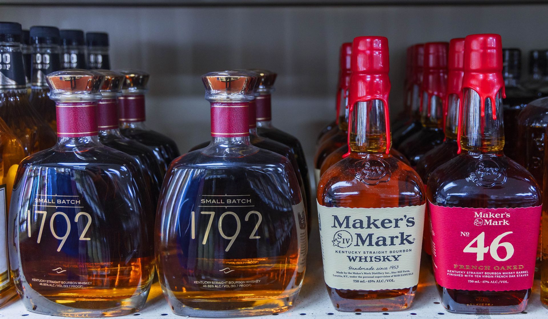 Bottles of bourbon on a shelf; including 1792, Maker's Mark, and Maker's Mark 46 with red wax seals.